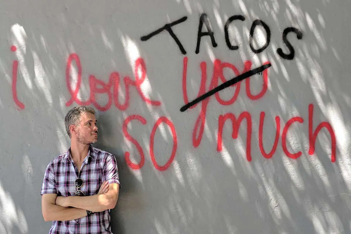Bret McGowen in front of a sign that says I Love Tacos